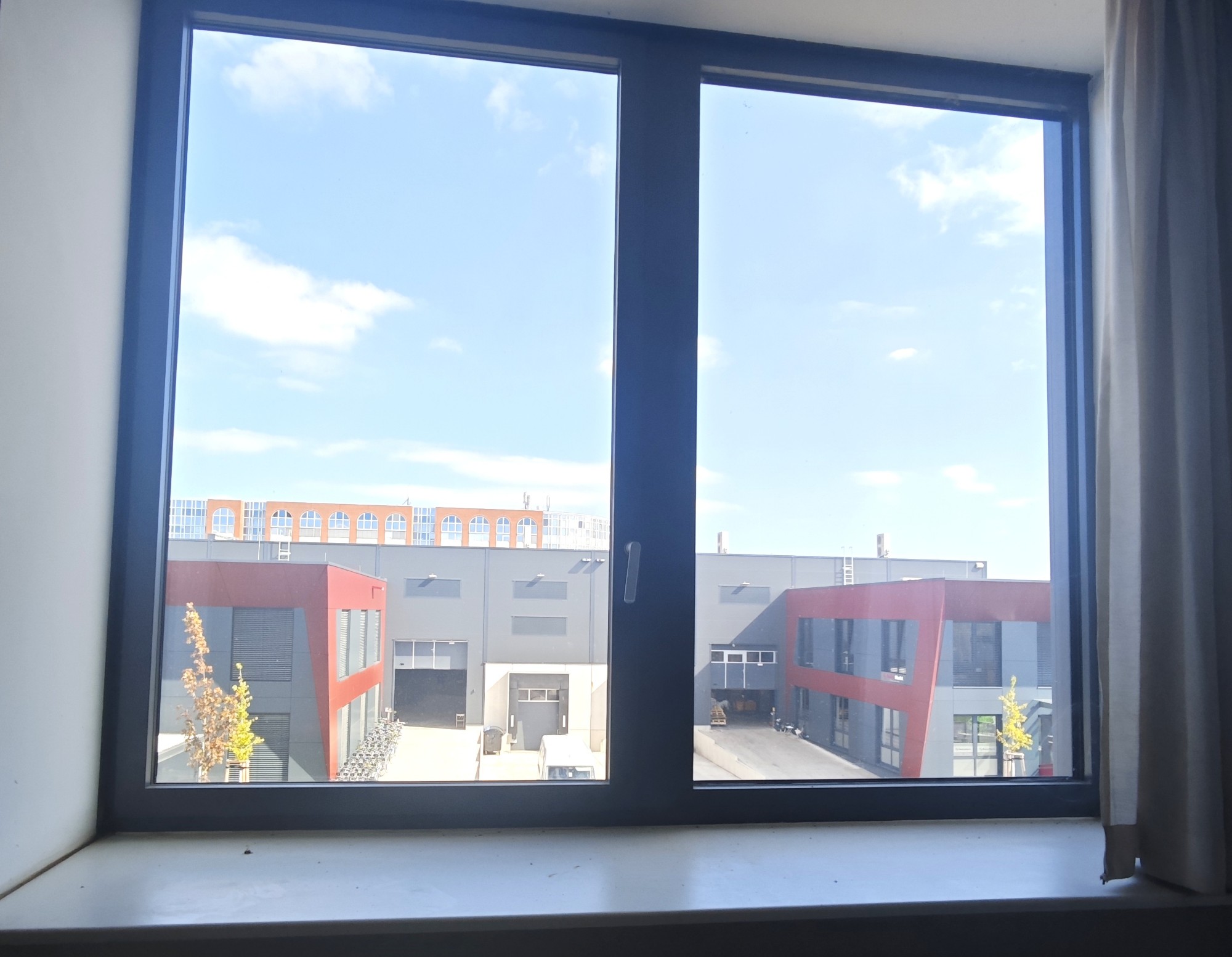 Blick aus dem Fenster von Einheit 1.08 auf die benachbarten Gewerbebauten mit Ladezonen