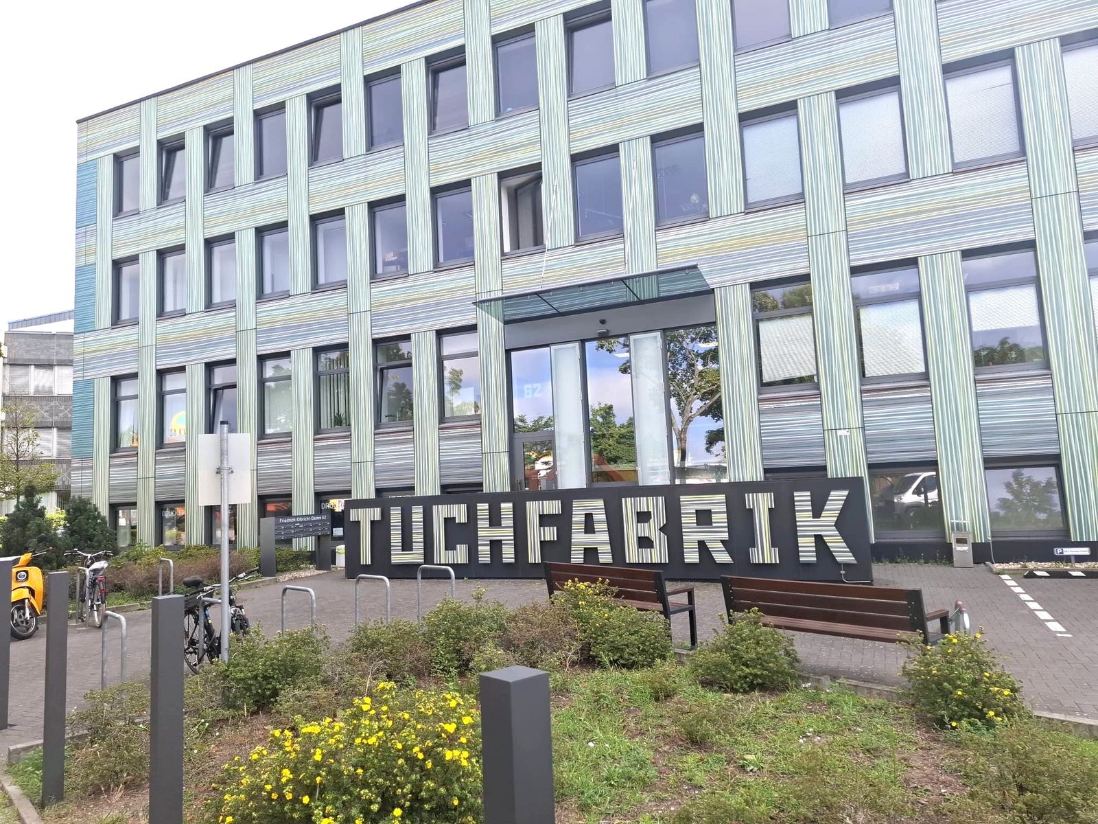 Eingang der Tuchfabrik Berlin mit Schriftzug an der gestreiften Fassade